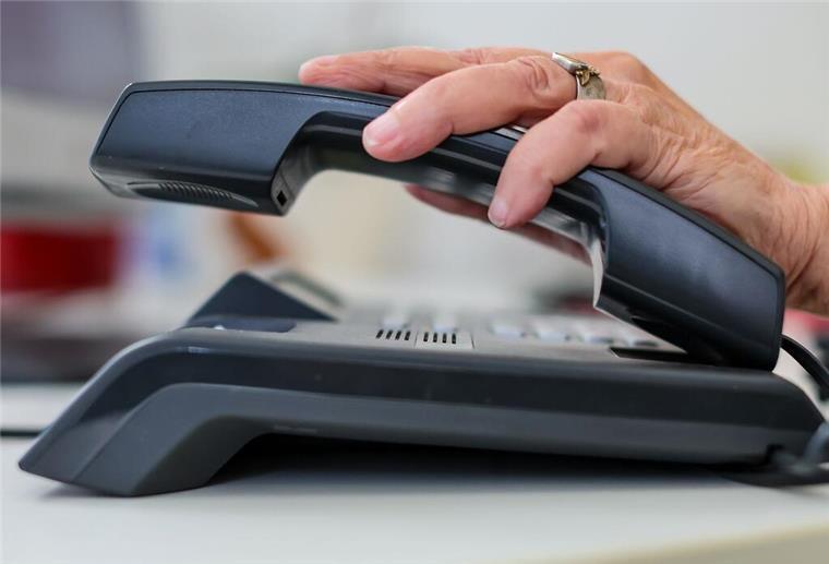 Eine Frau nimmt einen Telefonhörer in die Hand.