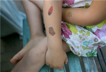 Ein Kinderarm mit Klebetattoos. 