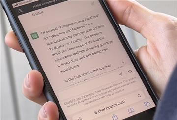 Eine Frau hält ein Smartphone mit der geöffneten Anwendung ChatGPT in der Hand. 