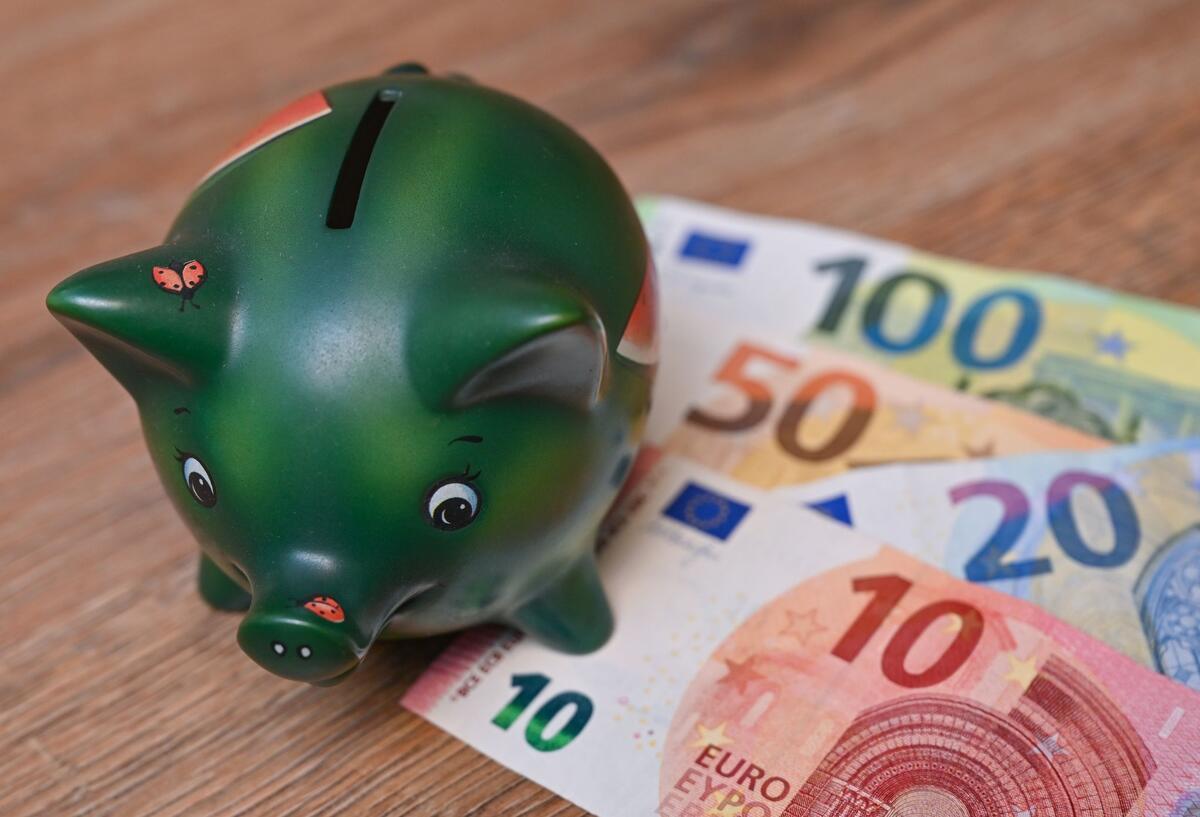 Trotz Preissteigerungen: So viel sparen die Deutschen im Monat Ein Sparschwein steht auf einem Tisch neben Eurobanknoten.