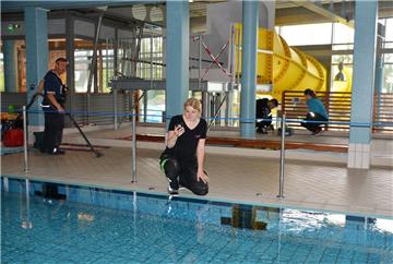 27,7 Grad sollen es sein: Leonie Sticht prüft die Wassertemperatur im Sportbecken. Nando Gutschera, Oliver Webb und Stephanie Schories reinigen unter dem künftigen Rutschen-Startbecken.