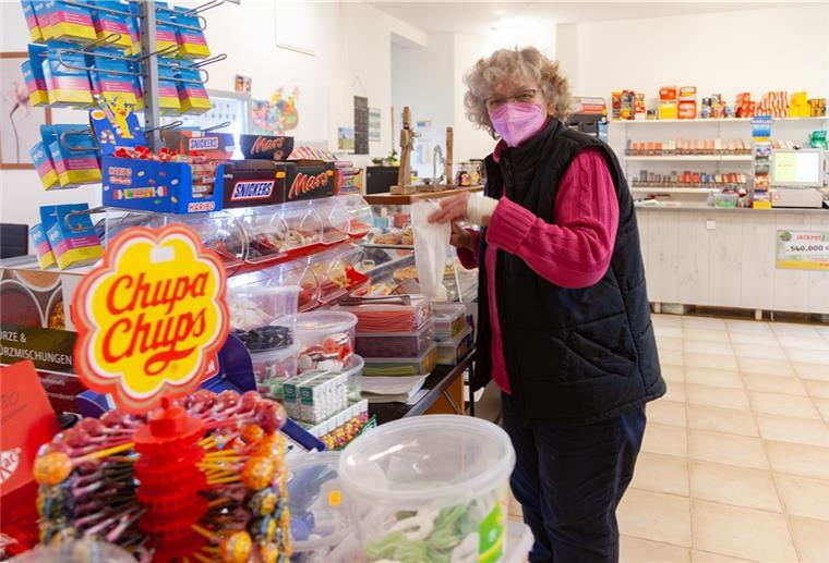 Eine Kioskbetreiberin hält eine Tüte in der Hand.