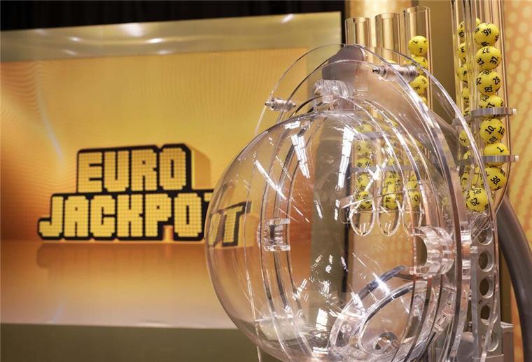 28 Euro Einsatz und ein anonymer Lottoschein! Das ist über den Eurojackpot-Gewinn bekannt Die Lostrommel des Eurojackpots steht im Vordergrund. Im Hintergrund steht der Schriftzug Eurojackpot.