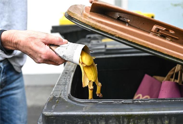 Neue EU-Regel gilt: Mülltonnen werden jetzt knallhart kontrolliert Eine Frau wirft in Zeitungspapier gewickelte Bananenschalen in eine Mülltonne für den Biomüll.