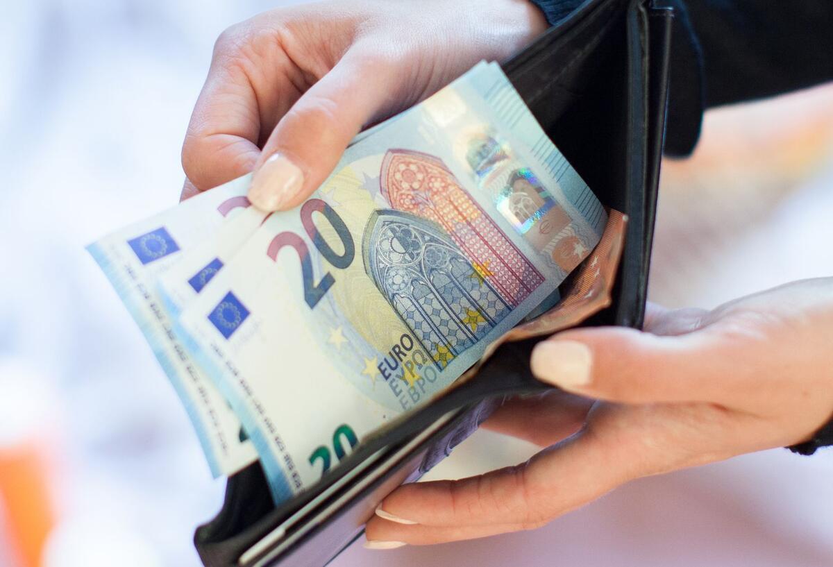 Bargeld in einem Portemonaie in den Händen einer Frau.