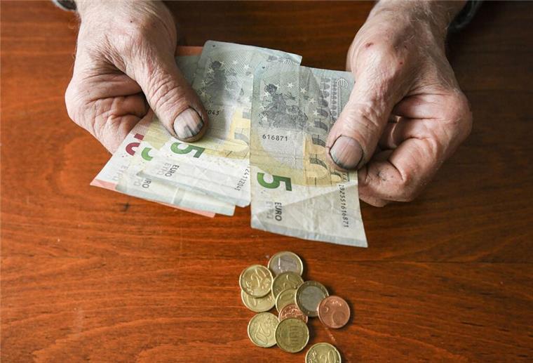 Eine ältere Person hält Euroscheine in der Hand. 