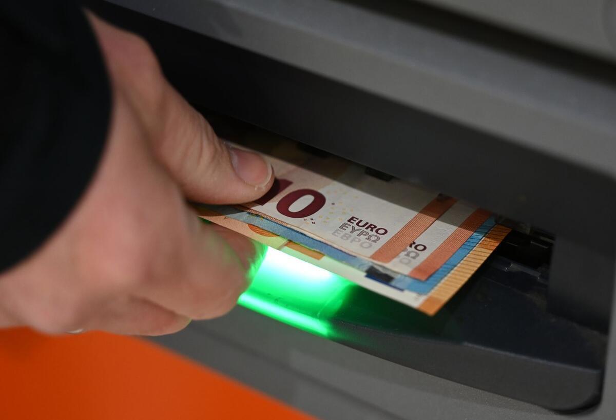 Bargeldgrenze 2027: Handwerk und Autohandel in Aufruhr Ein Mann zieht Geldscheine aus dem Ausgabefach eines Geldautomaten.