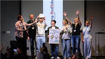 Abgesandte der Hellweg Realschule in Unna-Massen (Nordrhein-Westfalen) stehen zusammen mit Moderator „Checker“ Julian Janssen (l) bei der Verleihung der Hauptpreise des bundesweiten Wettbewerbs „Toiletten machen Schule“ beim 1. Deutschen Schultoilettengipfel der German Toilet Organization (GTO) auf der Bühne.