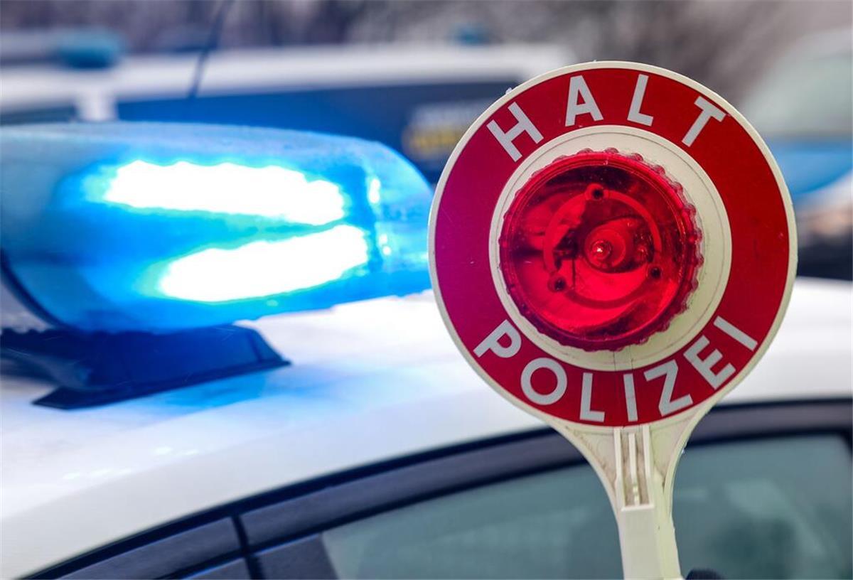  Ein Polizist hält eine Polizeikelle für eine Kontrolle auf einem Parkplatz an der Autobahn. 
