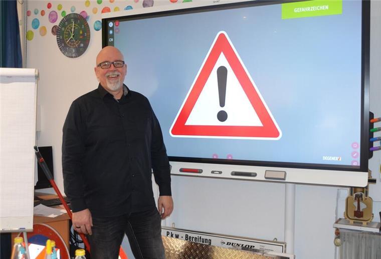 Fahrschule Lücken zieht in andere Räumlichkeiten Fahrlehrer steht vor einer Leinwand mit Verkehrsschild.