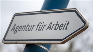 „Agentur für Arbeit“ steht auf einem Wegweiser vor einer Behörde.