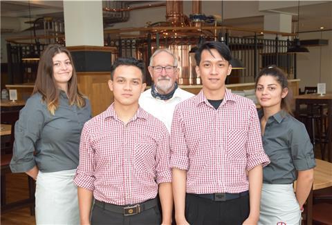Agus Wiranto (links) und Hadi Hisyam Mustawan haben eine lange Reise auf sich genommen, um in Deutschland eine Ausbildung zu beginnen. Die Indonesier sind ab sofort Teil des Teams des Butjadinger Tors in Abbehausen. Ihre Patenschaft haben Anienne Cosmann (hintere Reihe, links) und Andjela Djordjevic übernahmen. Auch Gastronom Udo Venema unterstützt die beiden Neuen tatkräftig.