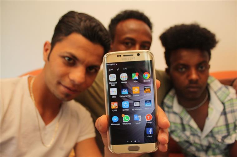 Ahmed Naser aus Syrien (von links), Yemane Gebremeskel und  Ghergish Gherensie Weldezgi aus Eritrea mit dem Smartphone. Foto Gehrke