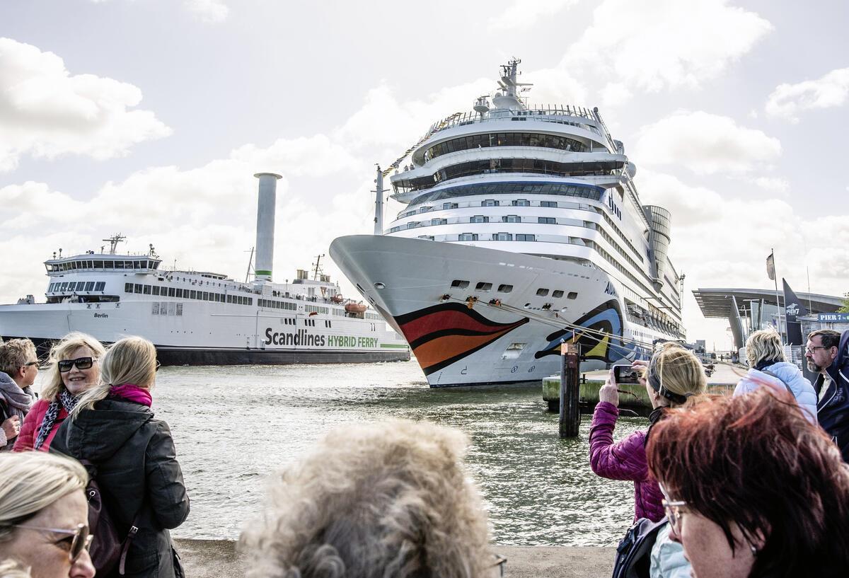 Menschen schauen auf ein Schiff von AIDA.