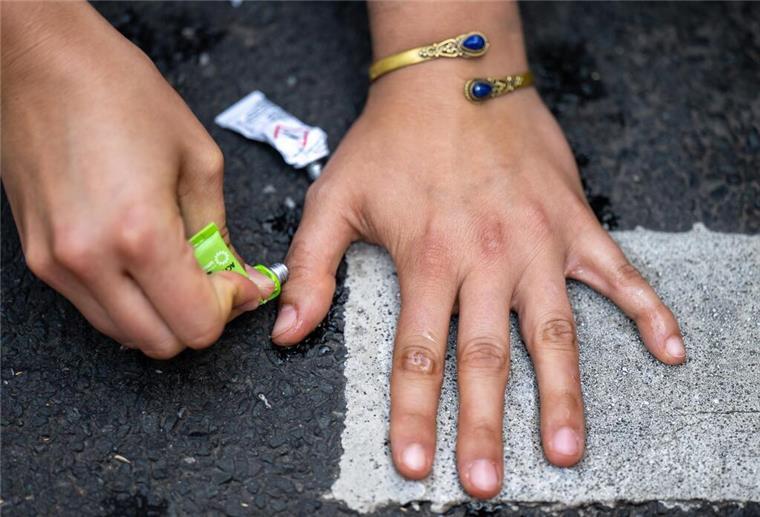 „Letzte Generation“ blockiert Verkehr in Bremen Die Hand einer Klimaaktivistin der Gruppe «Letzte Generation» klebt auf einer Straße. Nur wenige Minuten nach dem Freispruch für fünf Mitglieder der «Letzten Generation» vom Vorwurf der Nötigung haben die Klimaaktivisten eine Hauptverkehrsstraße blockiert. Zehn Frauen und Männer setzten sich auf eine Kreuzung und protestierten gegen die Folgen der Klimakrise. +++ dpa-Bildfunk +++