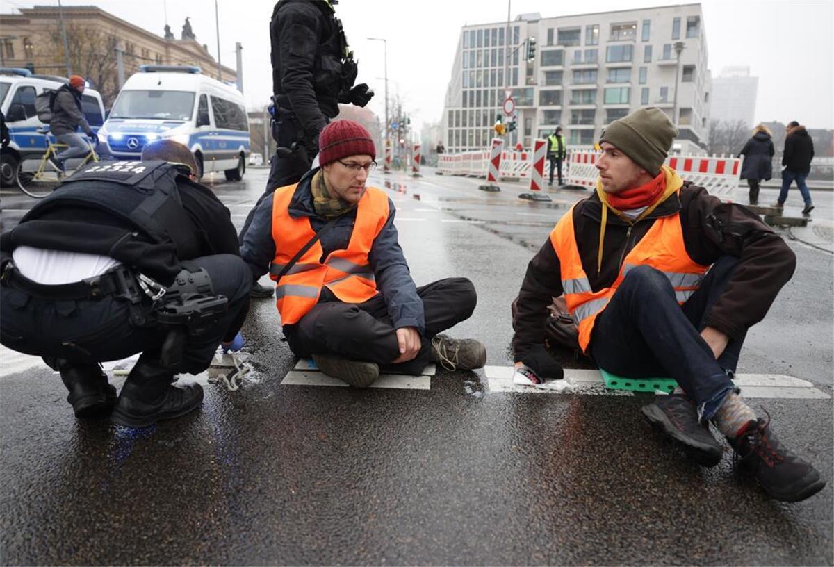 Ein Jahr "Klimakleber": Letzte Generation will Aktionen ausweiten Polizisten lösen die Hand eines Klimaaktivisten vom Asphalt auf der Invalidenstraße.
