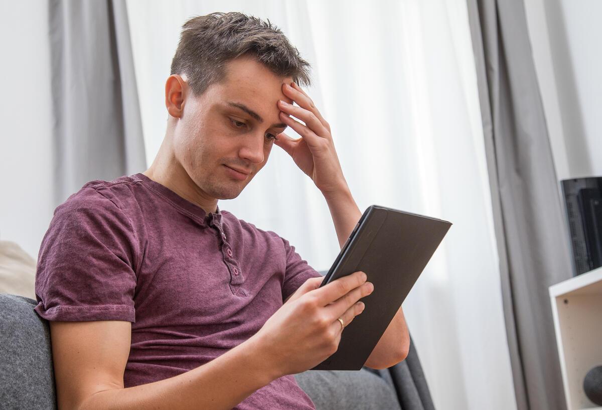 Millionen betroffen! E-Mail-Phishing: Telekom warnt vor Fake-Rechnungen Ein Mann fasst sich an den Kopf und hält ein Tablet in der Hand.