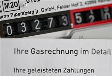 Eine Gasrechnung wird vor einen Gaszähler in einem privaten Haushalt gehalten. 