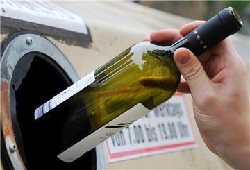 Eine Glasflasche wird in einen Container geworfen