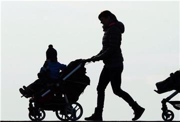 Eine Mutter schiebt einen Kinderwagen. 