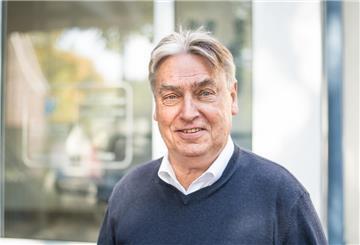 Ein Mann lächelt in die Kamera.