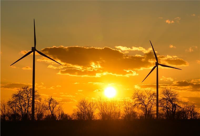 Brandenburg, Sieversdorf: Farbenprächtig leuchtet der Sonnenuntergang hinter zwei Windenergieanlagen im Windenergiepark «Odervorland» im Landkreis Oder-Spree.
