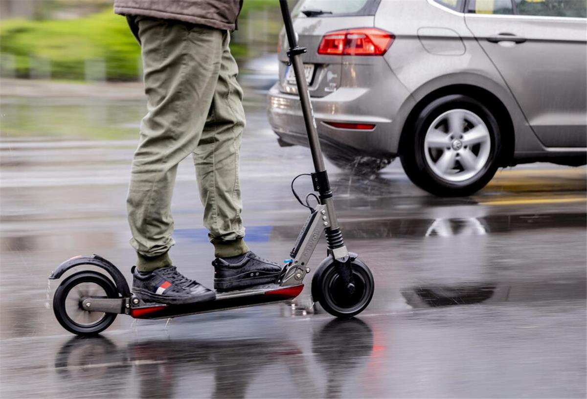 Ein Mann fährt mit einem E-Scooter auf der Straße.