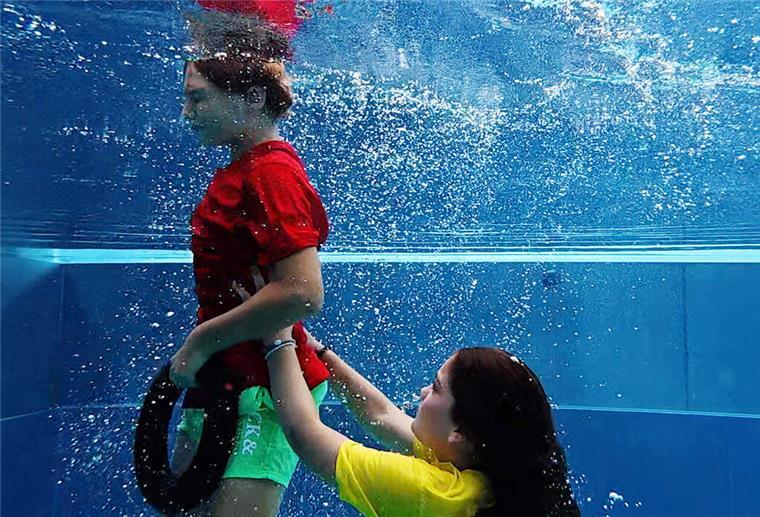 Kleine Helden - Schulkinder retten Kind vor dem Ertrinken Leo und Marlene demonstrieren mit einem Tauchring die Rettung einer Person aus einem Schwimmbecken.