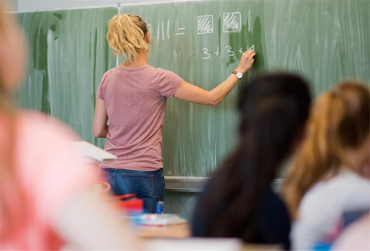 Eine junge Lehrerin schreibt in einer Schule in Niedersachsen an eine Schultafel.