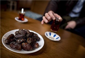 Eine Person trinkt einen Tee während Essen auf dem Tisch steht. Am 28. Februar beginnt der Ramadan 2025.