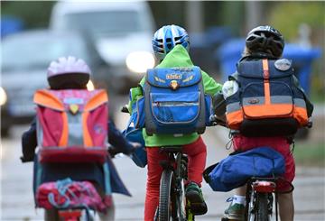 Kinder sind auf einer Straße mit dem Fahrrad unterwegs zur Schule.