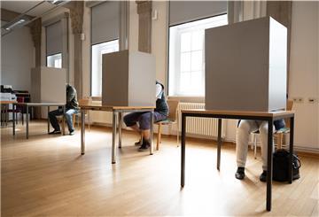 Wahlberechtigte sitzen in einem Briefwahlbüro im Bürgersaal des Stadthauses in einer Wahlkabine.