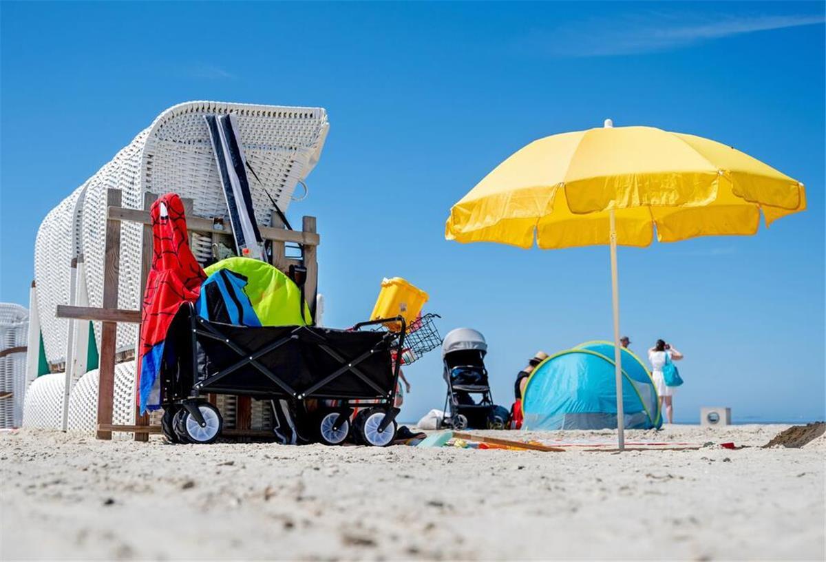Saftige Strafen drohen! Diese Fehler am Strand von Sylt und Co. besser vermeiden Ein Sonnenschirm steht bei sonnigem Wetter neben einem Strandkorb am Strand von Norddeich.
