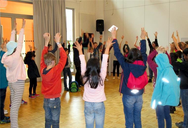 Kinder stehen im Kreis und recken die Hände in die Höhe. 