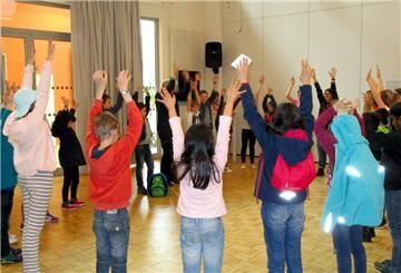 Kinder stehen im Kreis und recken die Hände in die Höhe. 