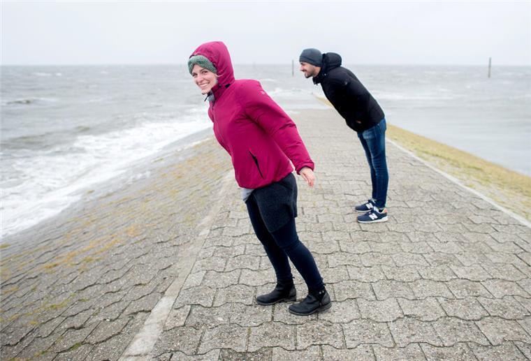 zwei Personen stemmen sich an der Nordsee gegen den Wind