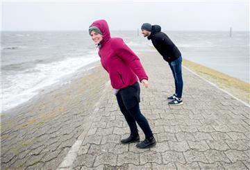 zwei Personen stemmen sich an der Nordsee gegen den Wind