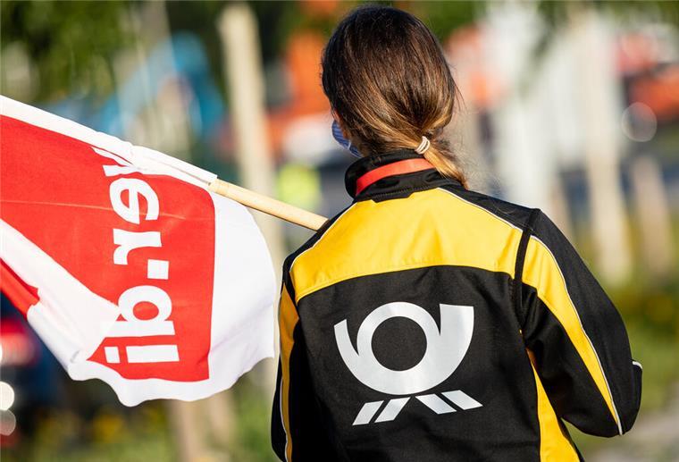 Bremen und Niedersachsen: Weitere Warnstreiks von Post-Zustellern Eine Beschäftigte der Deutschen Post steht mit einer Fahne der Gewerkschaft Verdi vor der Deutsche-Post-DHL-Niederlassung