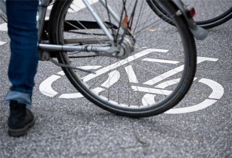 Ein Fahrrad-Symbol ist auf der Fahrbahn einer Straße hinter einem Fahrrad zu sehen.
