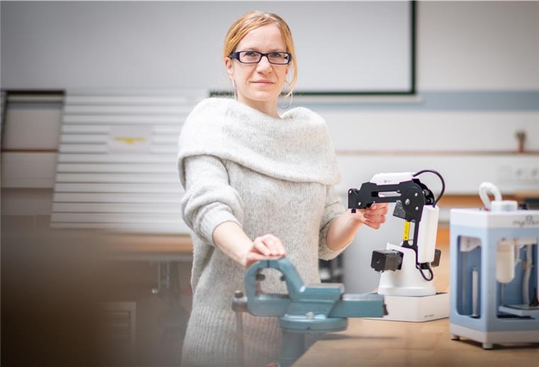 Eine Frau zeigt einen Leichtroboter. 