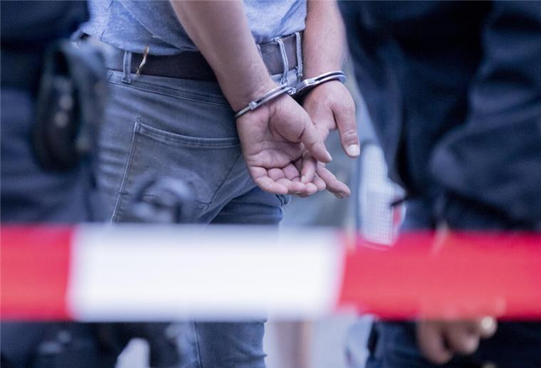 Nach Festnahme von Trainer: Verein bietet Mitgliedern Gespräche an Eine mit Handschellen gefesselte Person steht am Rande einer Kundgebung gegen die Corona-Beschränkungen auf der Straße des 17. Juni neben Polizisten. Die Polizei hat die Veranstaltung aufgelöst. Zu der Demonstration gegen Corona-Maßnahmen hat die Initiative «Querdenken 711» aufgerufen. Das Motto der Demonstration lautet «Das Ende der Pandemie - Tag der Freiheit» +++ dpa-Bildfunk +++
