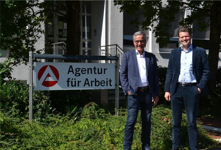 Über dem Arbeitsmarkt lacht die Sonne Oliver Lemke und Gregor Stein stehen neben dem Schild vor dem Eingang der Arbeitsagentur in Rotenburg