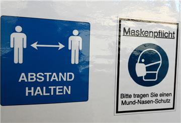 Ein Warnschild mit Coronaregeln hängt in einem Gebäude