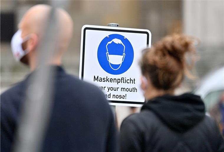 Cuxland: Kreis berät über neue Corona-Maßnahmen Zwei Menschen stehen vor einem Schild auf dem "Maskenpflicht" steht.