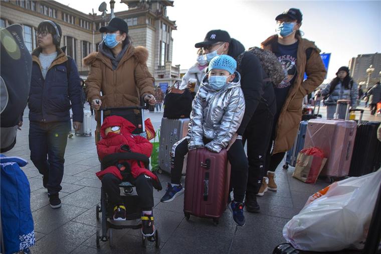 Angst vor einer neuartigen Lungenkrankheit: Reisende stehen mit Rollkoffern in der Nähe des Pekinger Bahnhofs und tragen Mundschutz. 


