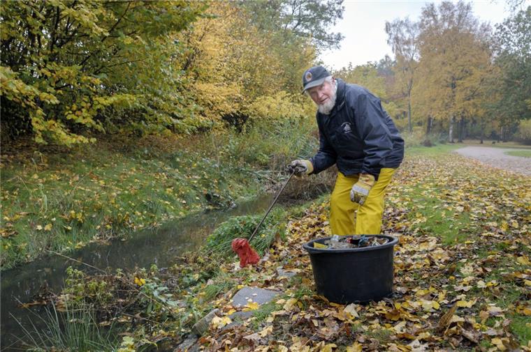 Anwohner Günter Schwellnus fischt Müll aus dem Graben Moorhöfe.
