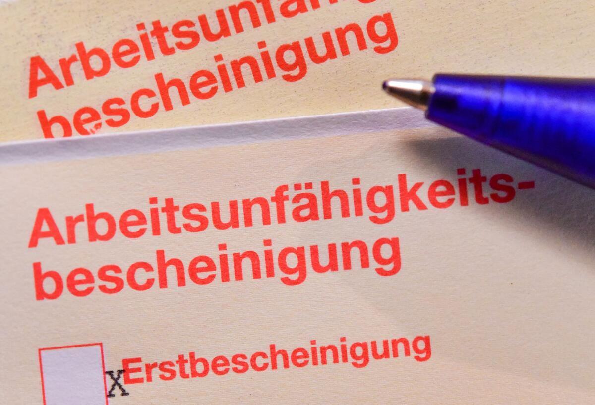Eine Arbeitsunfähigkeitsbescheinigung, auch Krankschreibung oder „Gelber Schein“ genannt, liegt auf einem Tisch.