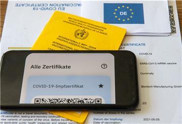 ARCHIV - 14.06.2021, Bayern, Augsburg: Ein Impfpass und ein Smartphone, auf dem die App CovPass läuft, liegen auf einem Impfzertifikat, das von einer Apotheke ausgestellt wurde. Ohne Booster sind EU-Impfzertifikate künftig spätestens neun Monate nach der Grundimmunisierung ungültig. Die Entscheidung tritt am 1. Februar in Kraft, wie die EU-Kommission mitteilte. Foto: Stefan Puchner/dpa +++ dpa-Bildfunk +++