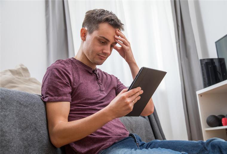 Ein Mann guckt auf ein Tablet. 