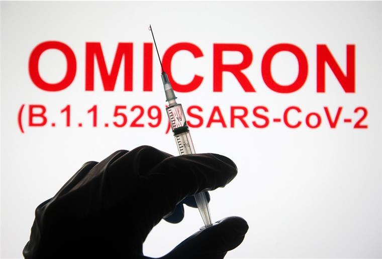 Corona-Variante Omikron in Deutschland angekommen Eine Hand hält vor der Aufschrift «Omicron (B.1.1.529): SARS-CoV-2» eine Spritze hoch.